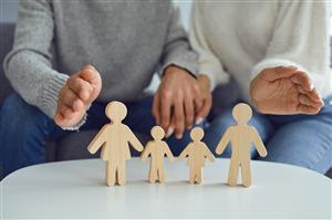 wooden cutout of a four person family with two hands wrapping around them in support 